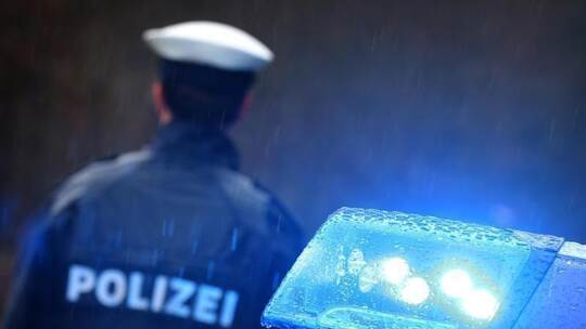 Ein Polizist vor einem Streifenwagen mit aktiviertem Blaulicht. Foto: Karl-Josef Hildenbrand/dpa