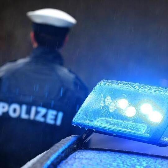 Ein Polizist vor einem Streifenwagen mit aktiviertem Blaulicht. Foto: Karl-Josef Hildenbrand/dpa