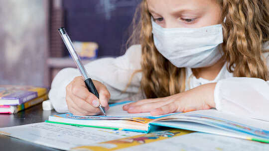 Child with face mask back at school after covid-19 quarantine and lockdown. Young elementary school girl with face protective ma