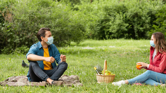 Couple have date during the coronavirus lockdown crisis. Man and woman in the park. Social distancing and virus protection.