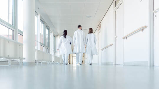 Three doctors walking down a corridor in hospital