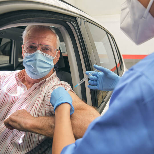 Crop doctor injecting COVID 19 vaccine into arm of patient