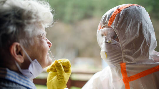 Taking corona virus test sample from nose of senior woman, quarantine concept.