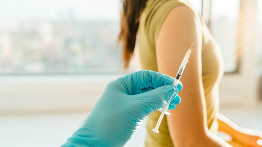 Vaccine against coronavirus at medical clinic banner. Woman being vaccinated with syringe held by healthcare professional worker