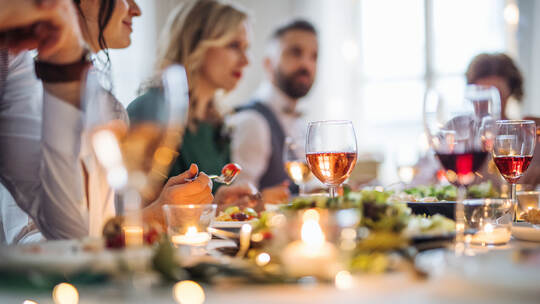 A big family sitting at a table on a indoor birthday party, eating.