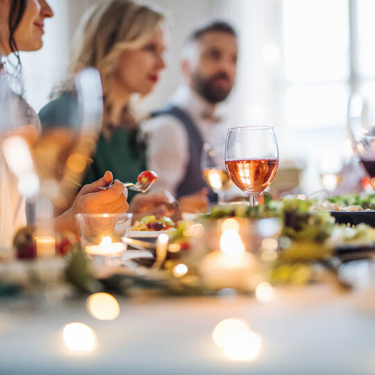 A big family sitting at a table on a indoor birthday party, eating.