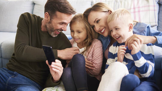 Family using mobile phone in living room