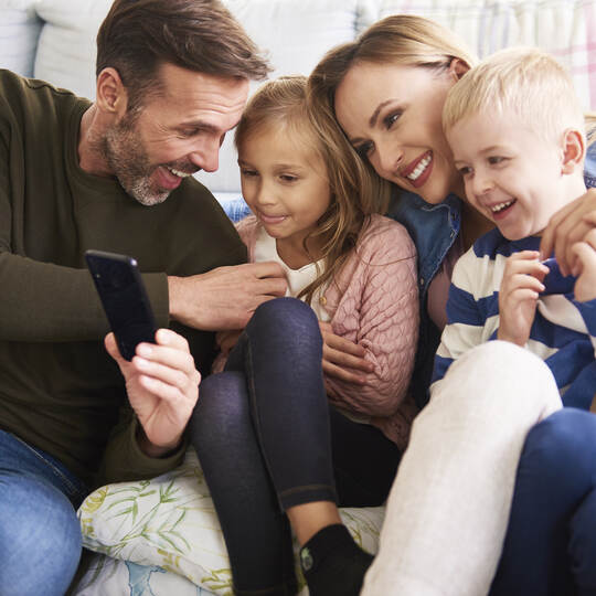 Family using mobile phone in living room
