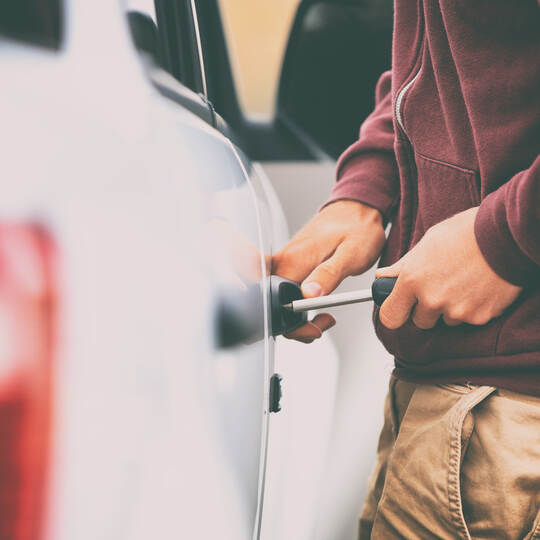 Car theft thief stealing vehicle. Street crime man breaking in automobile to steal.