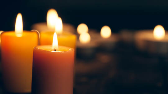 candles burning in darkness over black background. commemoration concept.