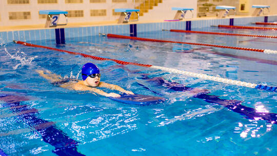 Down syndrome in swimming cap training in seimming pool sport club with trainer