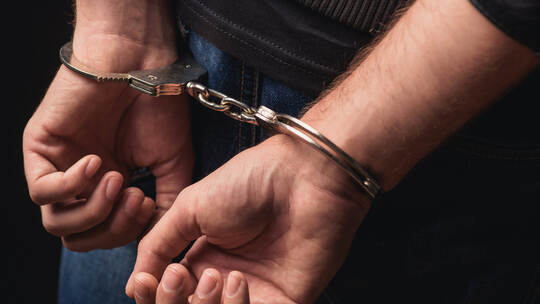 Young criminal standing in handcuffs
