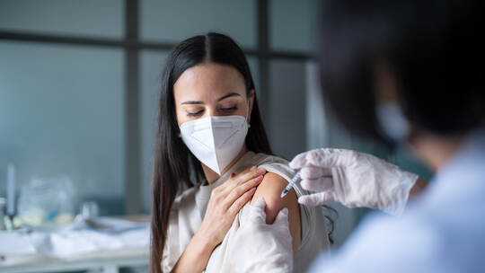 Woman with face mask getting vaccinated in hospital, coronavirus and vaccination concept.