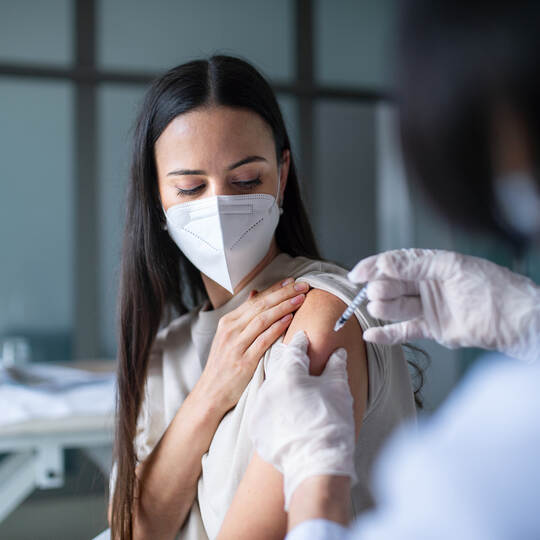 Woman with face mask getting vaccinated in hospital, coronavirus and vaccination concept.