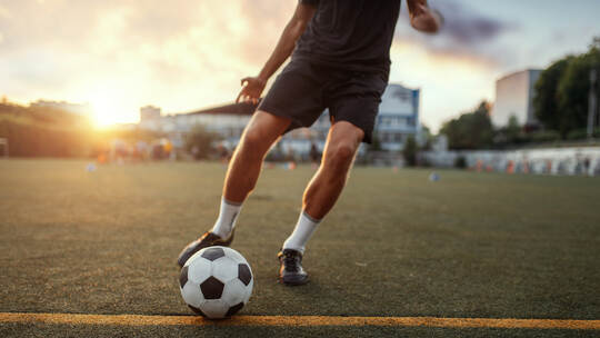 Male football player hits the ball on the field