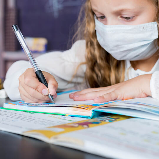 Child with face mask back at school after covid-19 quarantine and lockdown. Young elementary school girl with face protective ma