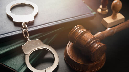 Arrest concept. Metal handcuffs near judge gavel