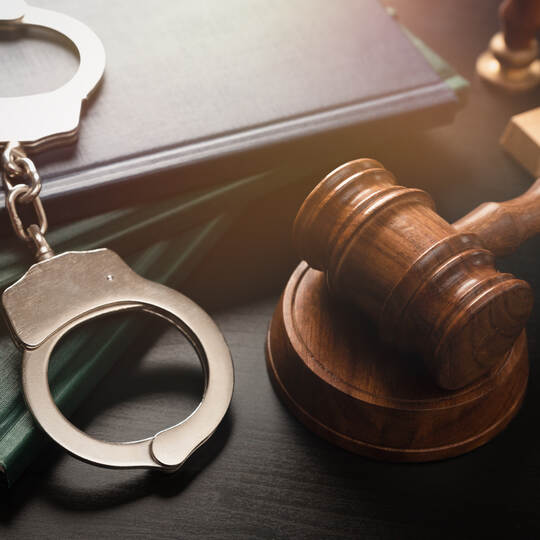 Arrest concept. Metal handcuffs near judge gavel