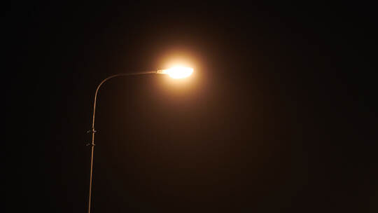 One night lamppost shines with faint mysterious yellow light through evening fog, copy space