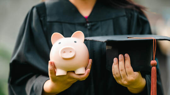 graduates holding piggy banks saving concept