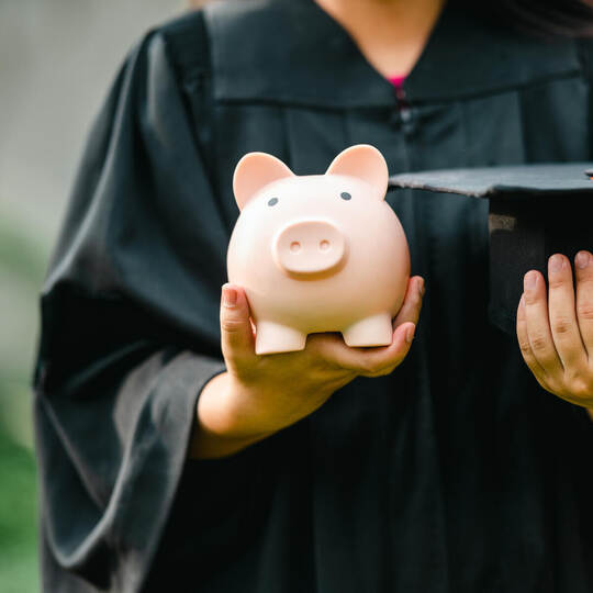 graduates holding piggy banks saving concept
