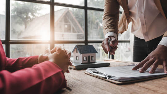 House model with agent and customer discussing for contract to buy, get insurance or loan real estate or property..