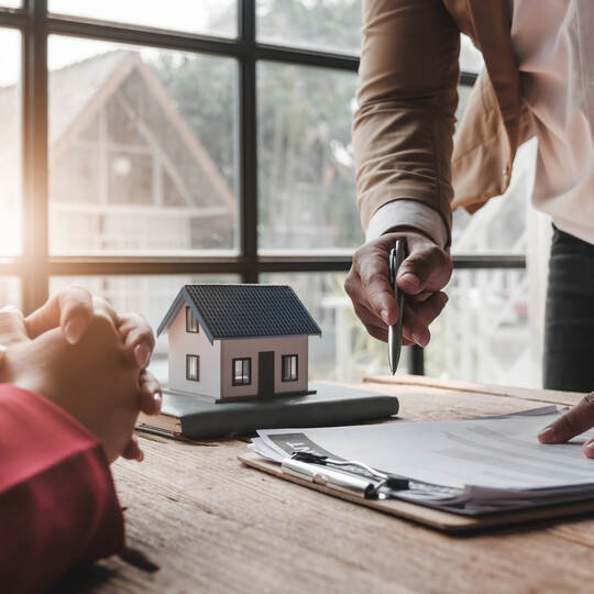 House model with agent and customer discussing for contract to buy, get insurance or loan real estate or property..