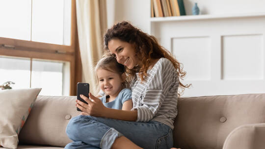 Smiling affectionate family of two posing for smartphone selfie.