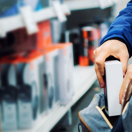 close up the consumer thief’s hands putting the new gadget in the pocket in the store