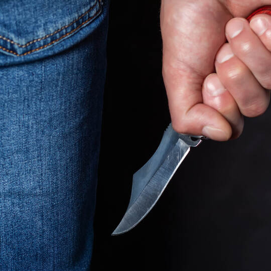 Man holding a knife in a threatening stance ready to fight