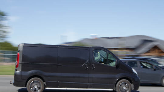 A black van is driving down the street at high speed. Motion blur