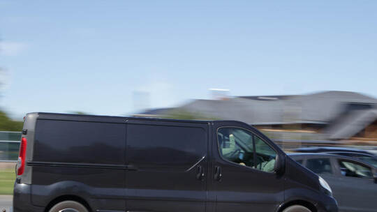 A black van is driving down the street at high speed. Motion blur