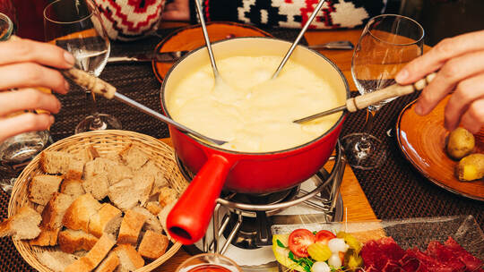 Friends eating cheese fondue in a cozy traditional swiss restaurant