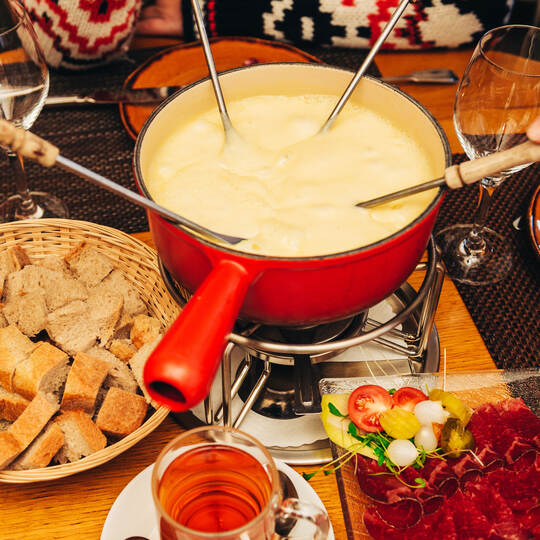 Friends eating cheese fondue in a cozy traditional swiss restaurant
