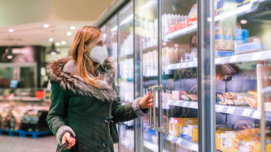 Woman at supermarket freezer section wearing face mask