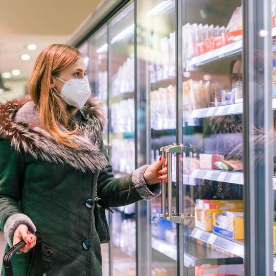 Woman at supermarket freezer section wearing face mask