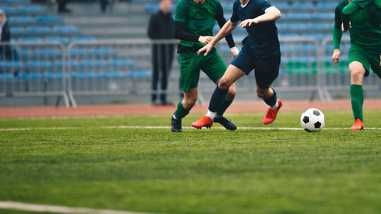Soccer players run a game and kick soccer ball. European football competition match between players in green and blue uniforms.