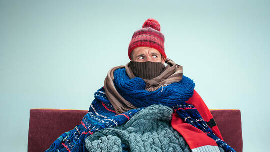 Bearded Man with Flue Sitting on Sofa at Home. Healthcare Concepts.