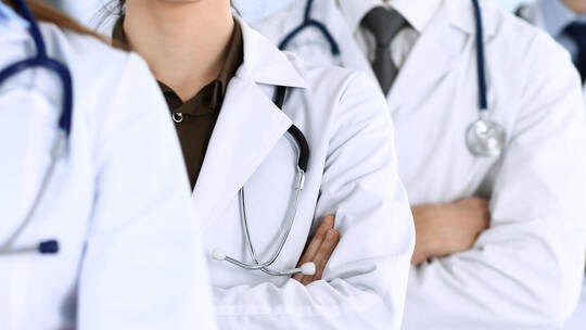 Group of modern doctors standing as a team with arms crossed in hospital office. Physicians ready to examine and help patients.