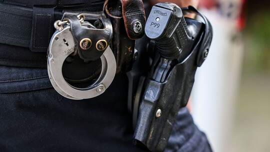 Ein Polizeibeamter hat eine Dienstwaffe am Gürtel. Ein Polizeibeamter hat eine Dienstwaffe am Gürtel.