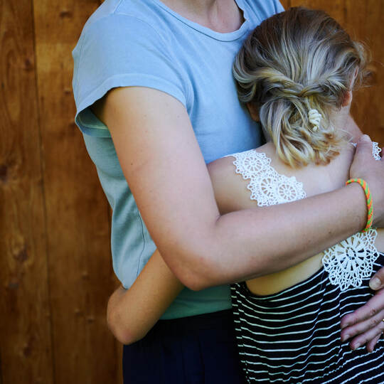 Ein Mädchen wird von seiner Mutter in den Arm genommen