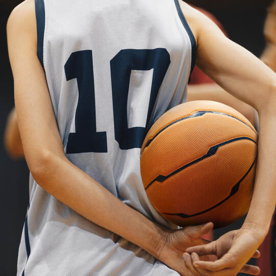 Junior level basketball player holding game ball. Basketball training session for kids