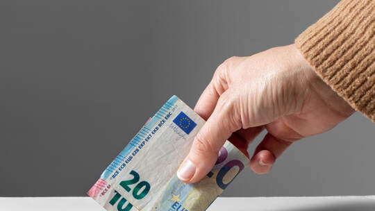 close up of hand putting money into donation box