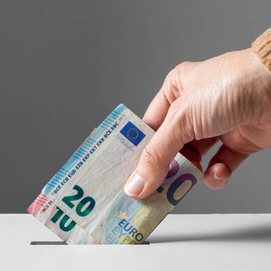 close up of hand putting money into donation box