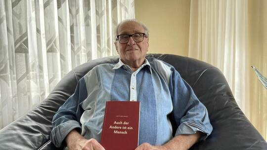 Der 90-jährige Gottlob Frick mit seinem Buch „Auch der Andere ist ein Mensch“, das er 2023 veröffentlichte. Derzeit arbeitet er