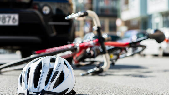 Close-up of a bicycling helmet on the asphalt next to a bicycle